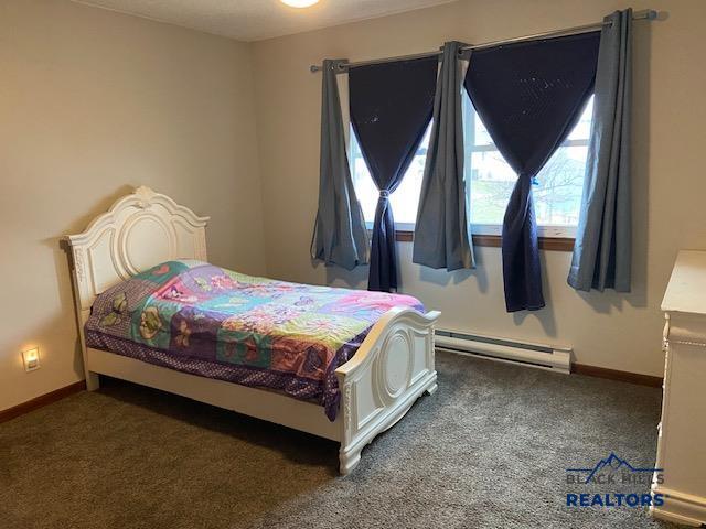 carpeted bedroom with baseboards and a baseboard heating unit