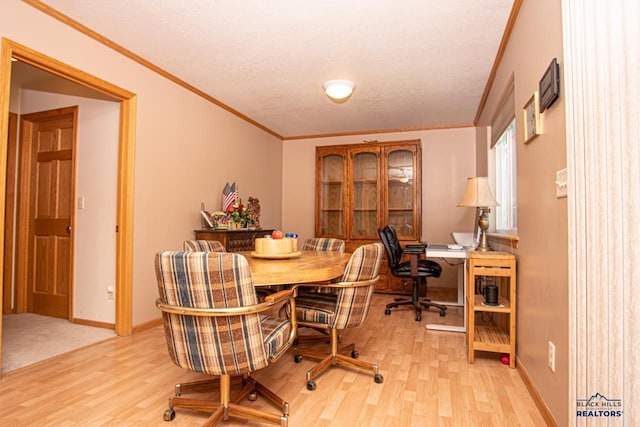 dining space with crown molding, light wood-style floors, a textured ceiling, and baseboards