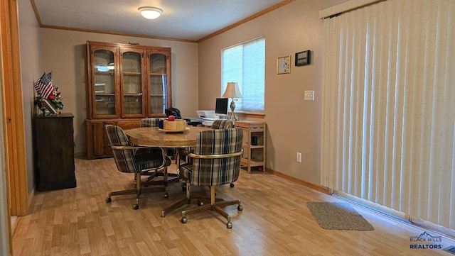 dining area featuring crown molding, light wood-type flooring, and baseboards