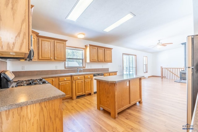 kitchen featuring light wood finished floors, dishwasher, gas stove, a sink, and a center island