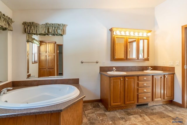bathroom featuring double vanity, visible vents, a sink, and a jetted tub