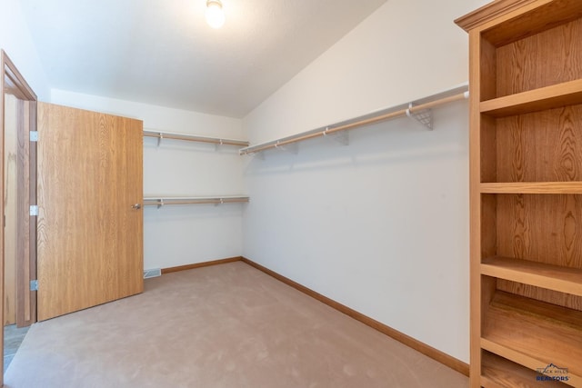 walk in closet with lofted ceiling and carpet