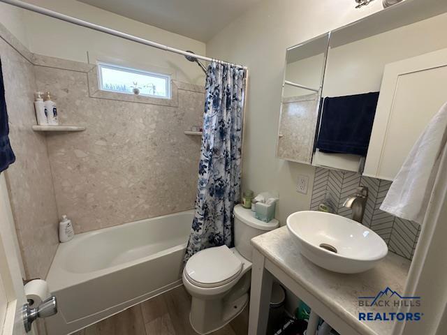 bathroom with toilet, a sink, shower / tub combo with curtain, and wood finished floors