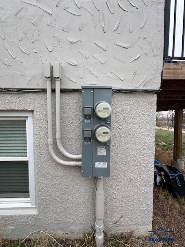 details featuring electric meter and stucco siding