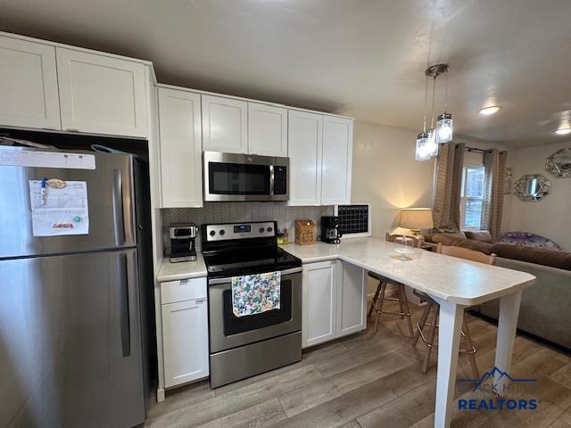 kitchen featuring decorative backsplash, light wood finished floors, stainless steel appliances, and open floor plan