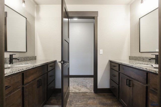 21260 Ridgewood Trl, Lead, SD 57754 - bathroom featuring stone finish floor, baseboards, a sink, and two vanities