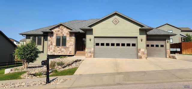 ranch-style house featuring fence, an attached garage, stone siding, and concrete driveway