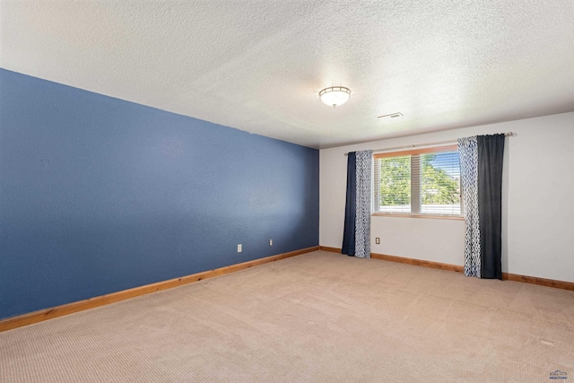 empty room featuring a textured ceiling, baseboards, light colored carpet, and visible vents