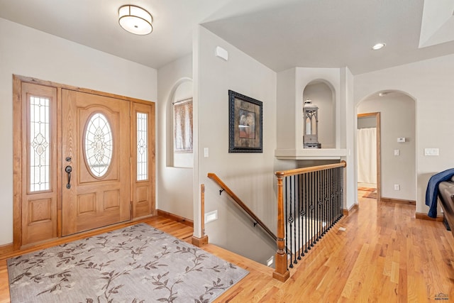 foyer entrance with arched walkways, recessed lighting, baseboards, and light wood-style floors