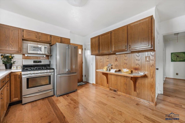 37 Washington St, Deadwood, SD 57732 - kitchen featuring visible vents, brown cabinetry, light wood-type flooring, and stainless steel appliances