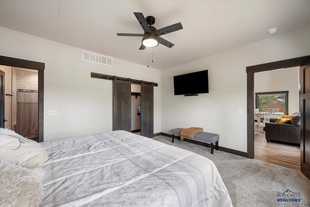 bedroom featuring carpet flooring, a barn door, baseboards, visible vents, and ceiling fan