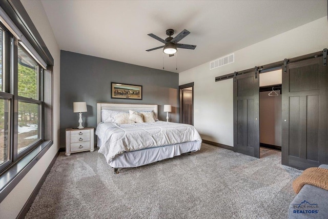 carpeted bedroom with baseboards, visible vents, a barn door, and ceiling fan
