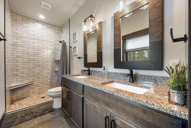 full bathroom with marble finish floor, a sink, toilet, and tiled shower