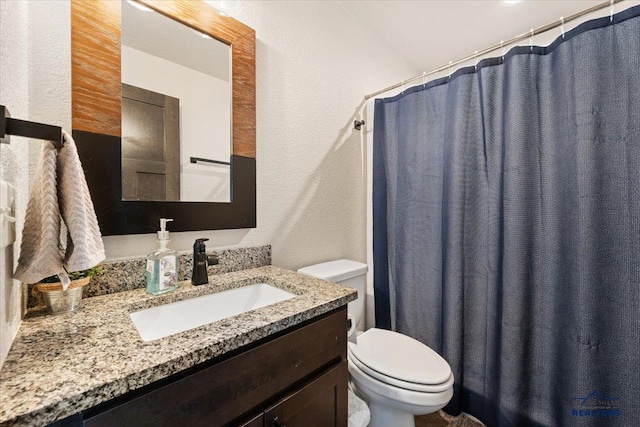 full bathroom featuring a textured wall, toilet, vanity, and a shower with shower curtain