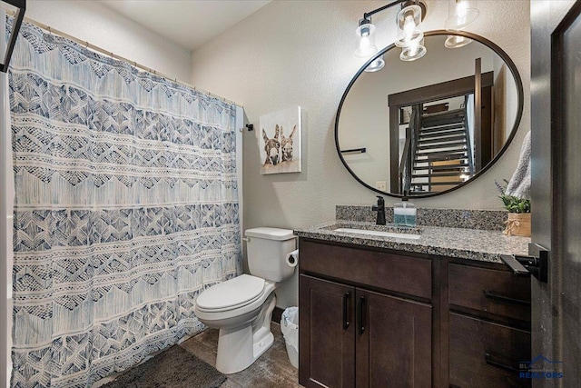 full bath with a textured wall, toilet, and vanity