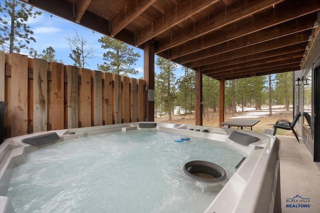view of patio featuring fence and a hot tub