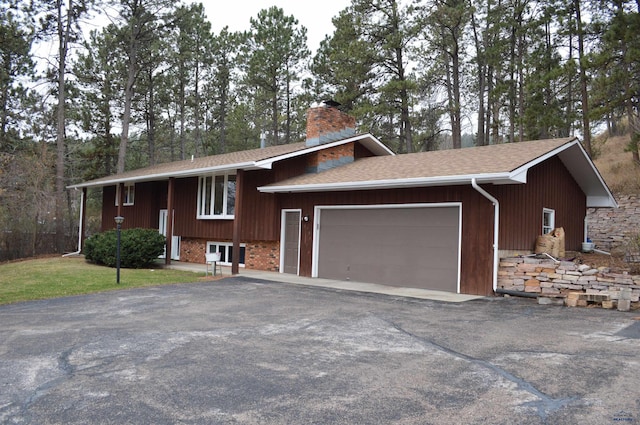 1521 Forest Ct, Rapid City, SD 57701 - bi-level home featuring roof with shingles, a chimney, an attached garage, and aphalt driveway