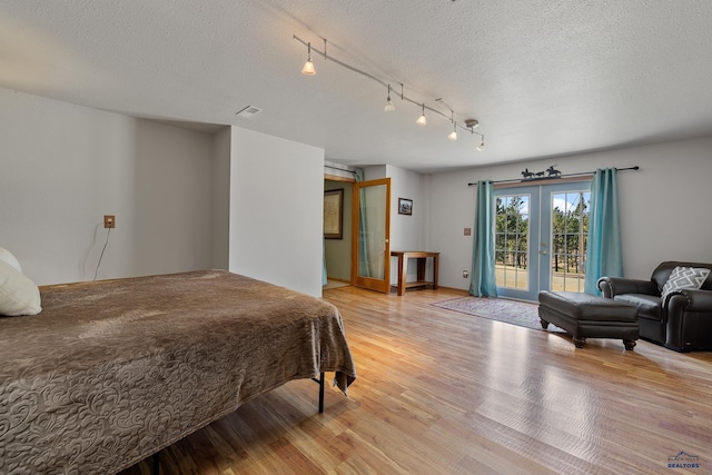 24354 Rushmore Ranch Rd, Keystone, SD 57751 - bedroom with french doors, access to exterior, light wood finished floors, and a textured ceiling