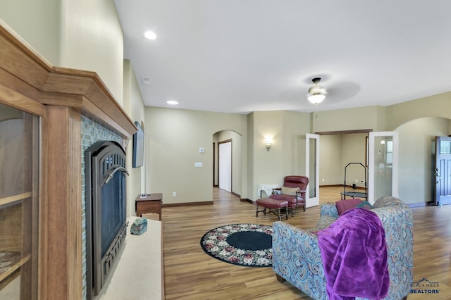 3129 Hazelnut Ln, Rapid City, SD 57703 - living area featuring arched walkways, a fireplace, a ceiling fan, and wood finished floors
