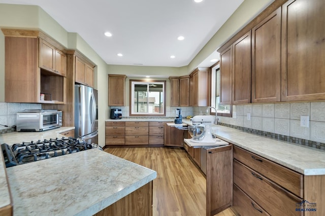 3129 Hazelnut Ln, Rapid City, SD 57703 - kitchen with brown cabinets, light wood-style flooring, freestanding refrigerator, a toaster, and backsplash