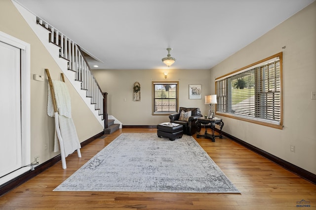 sitting room featuring baseboards, stairs, and wood finished floors