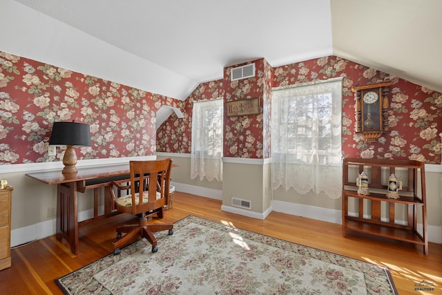 office space featuring wallpapered walls, visible vents, wood finished floors, and vaulted ceiling