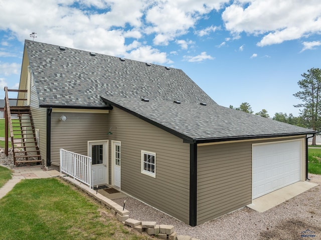 back of house featuring roof with shingles and stairs