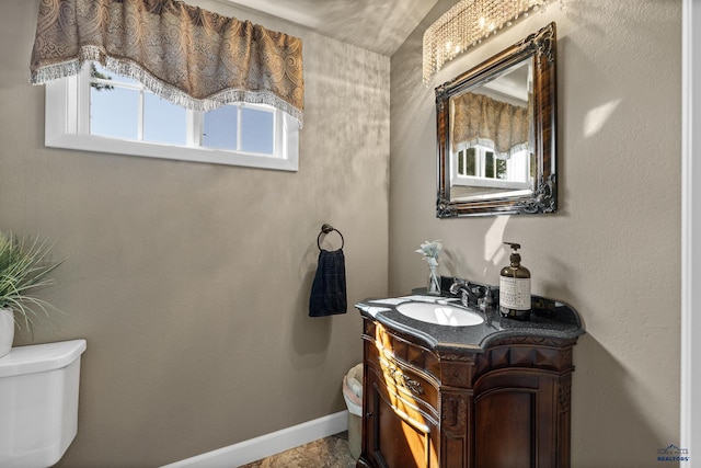 bathroom with toilet, vanity, and baseboards