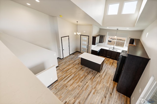 kitchen with a kitchen island, hanging light fixtures, a sink, and light wood-type flooring