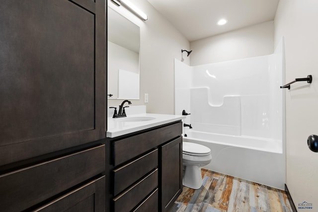bathroom featuring wood finished floors, toilet, vanity, and washtub / shower combination