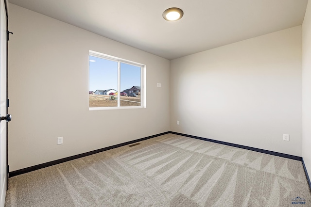carpeted spare room featuring baseboards and visible vents