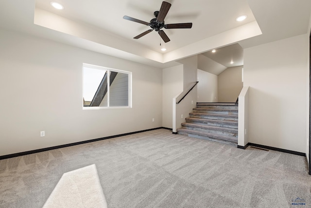 unfurnished living room featuring carpet, baseboards, recessed lighting, a ceiling fan, and a tray ceiling