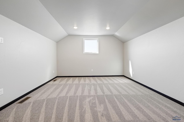 additional living space featuring light carpet, baseboards, visible vents, and vaulted ceiling