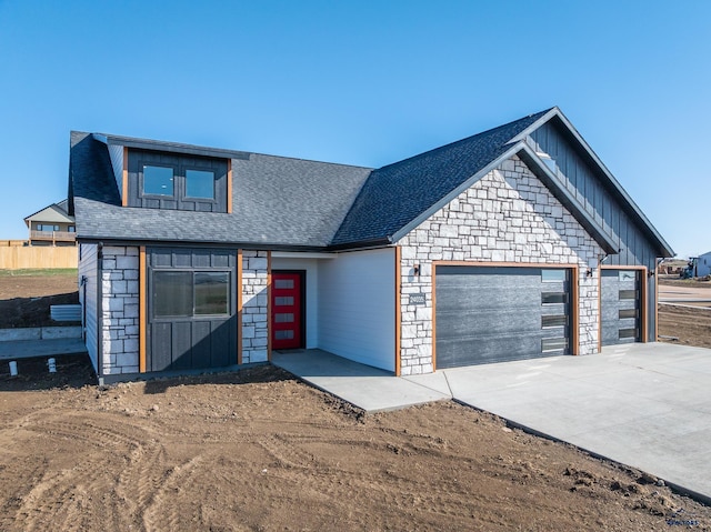 view of front of property featuring an attached garage, stone siding, board and batten siding, and concrete driveway