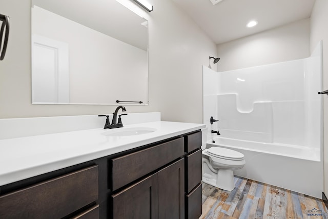 bathroom with toilet, vanity, wood finished floors, tub / shower combination, and recessed lighting