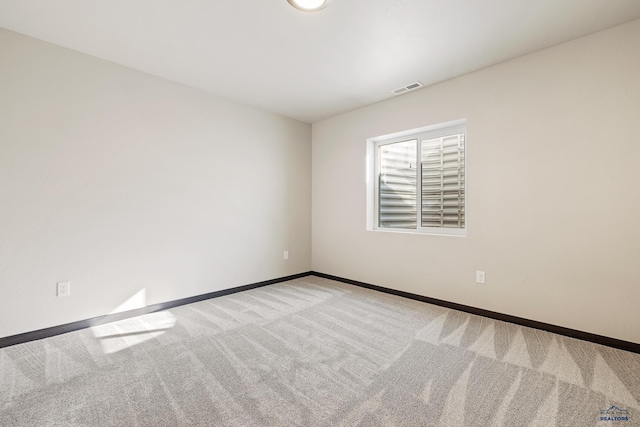 carpeted spare room featuring baseboards and visible vents