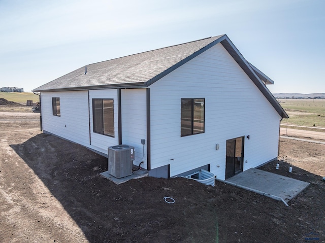 back of property with central air condition unit and a shingled roof