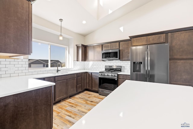 kitchen with tasteful backsplash, stainless steel appliances, a sink, light wood finished floors, and dark brown cabinetry