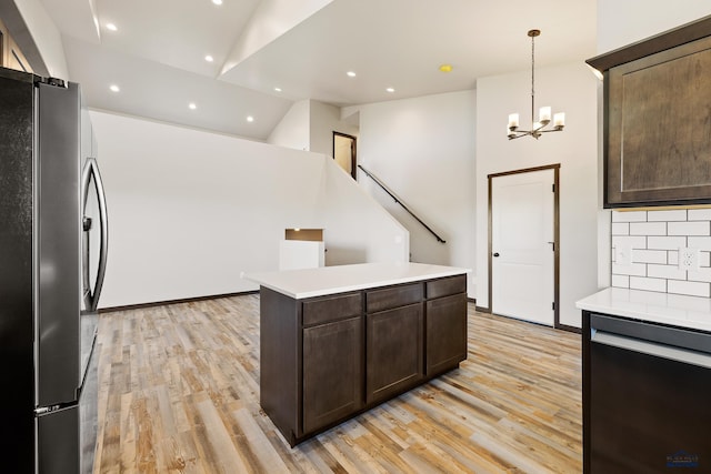 kitchen featuring light countertops, dark brown cabinetry, backsplash, freestanding refrigerator, and light wood-style flooring