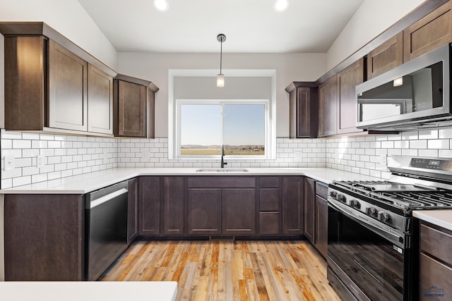 kitchen featuring a sink, light countertops, light wood-style flooring, and appliances with stainless steel finishes
