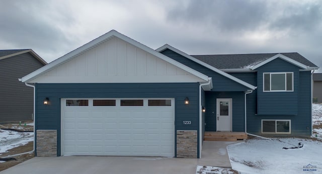 view of front of house featuring stone siding, board and batten siding, driveway, and an attached garage