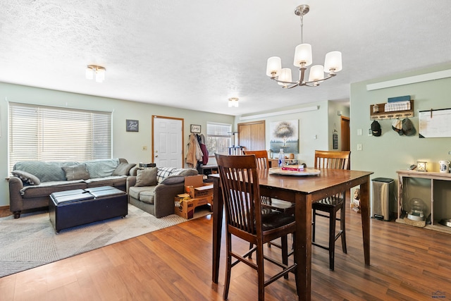 524 Mall Dr, Rapid City, SD 57701 - dining area featuring a textured ceiling, wood finished floors, and an inviting chandelier