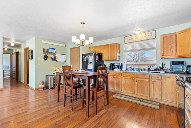 524 Mall Dr, Rapid City, SD 57701 - kitchen featuring an inviting chandelier, electric stove, a sink, freestanding refrigerator, and wood finished floors
