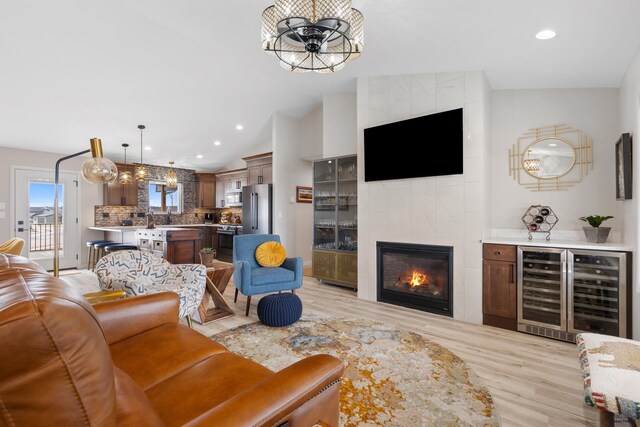 4403 Targhee Dr, Rapid City, SD 57702 - living area featuring a tile fireplace, a notable chandelier, light wood-style floors, and beverage cooler