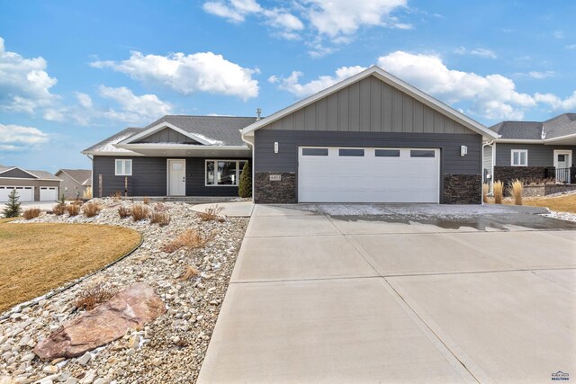 4403 Targhee Dr, Rapid City, SD 57702 - view of front of house with stone siding, a garage, board and batten siding, and concrete driveway