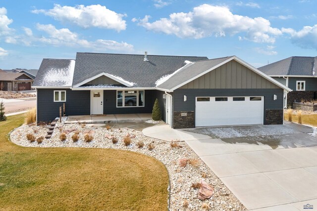 4403 Targhee Dr, Rapid City, SD 57702 - view of front of house with an attached garage, gravel driveway, board and batten siding, a front lawn, and a shingled roof