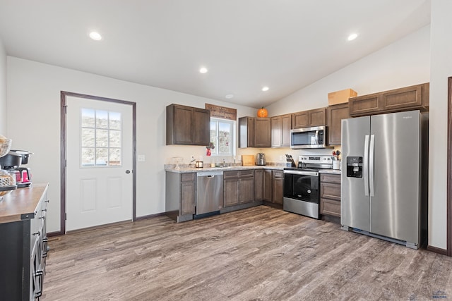 kitchen featuring stainless steel appliances, light wood-style floors, light countertops, and vaulted ceiling