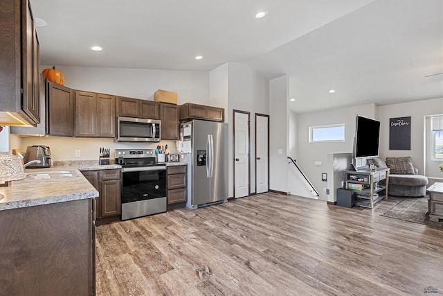 kitchen featuring light wood-style floors, light countertops, stainless steel appliances, open floor plan, and plenty of natural light