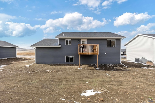rear view of property featuring cooling unit and roof with shingles