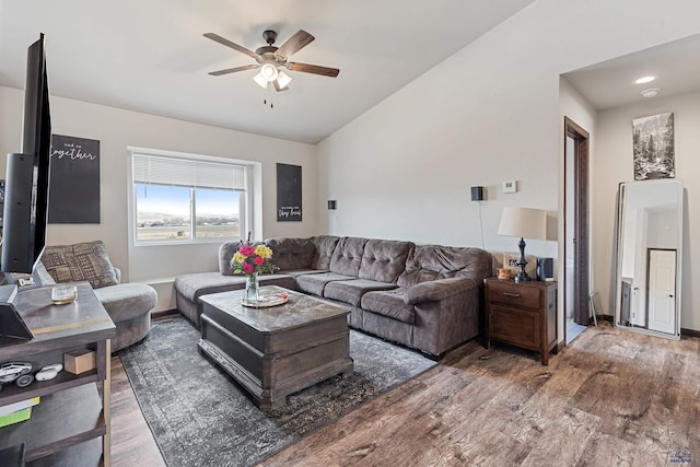 living area with ceiling fan, wood finished floors, vaulted ceiling, and baseboards